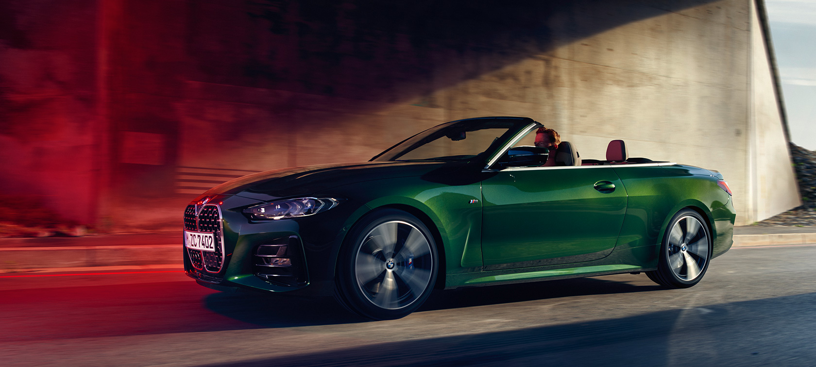 行駛中的BMW 4系列敞篷跑車車側 G23 行駛中的Sanremo Green銀粉漆車色的BMW 4系列敞篷跑車車側 G23