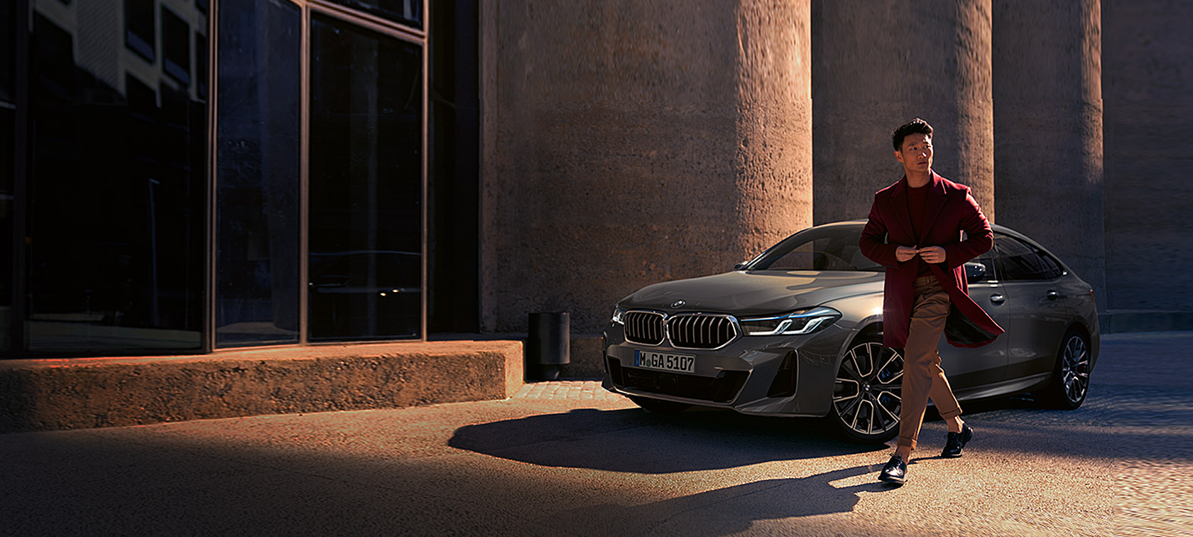 G32 BMW 6系列Gran Turismo 640i xDrive，Bernina Grey，靜止，四分之三車頭視角，男人於BMW前方