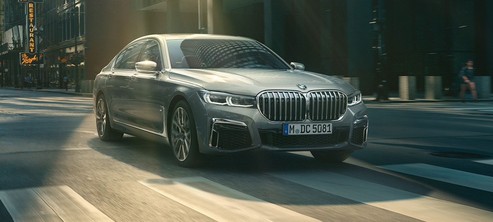 行駛中的灰色BMW 7系列四分之三車頭視角 行駛於都市的灰色BMW 7系列四分之三車頭視角