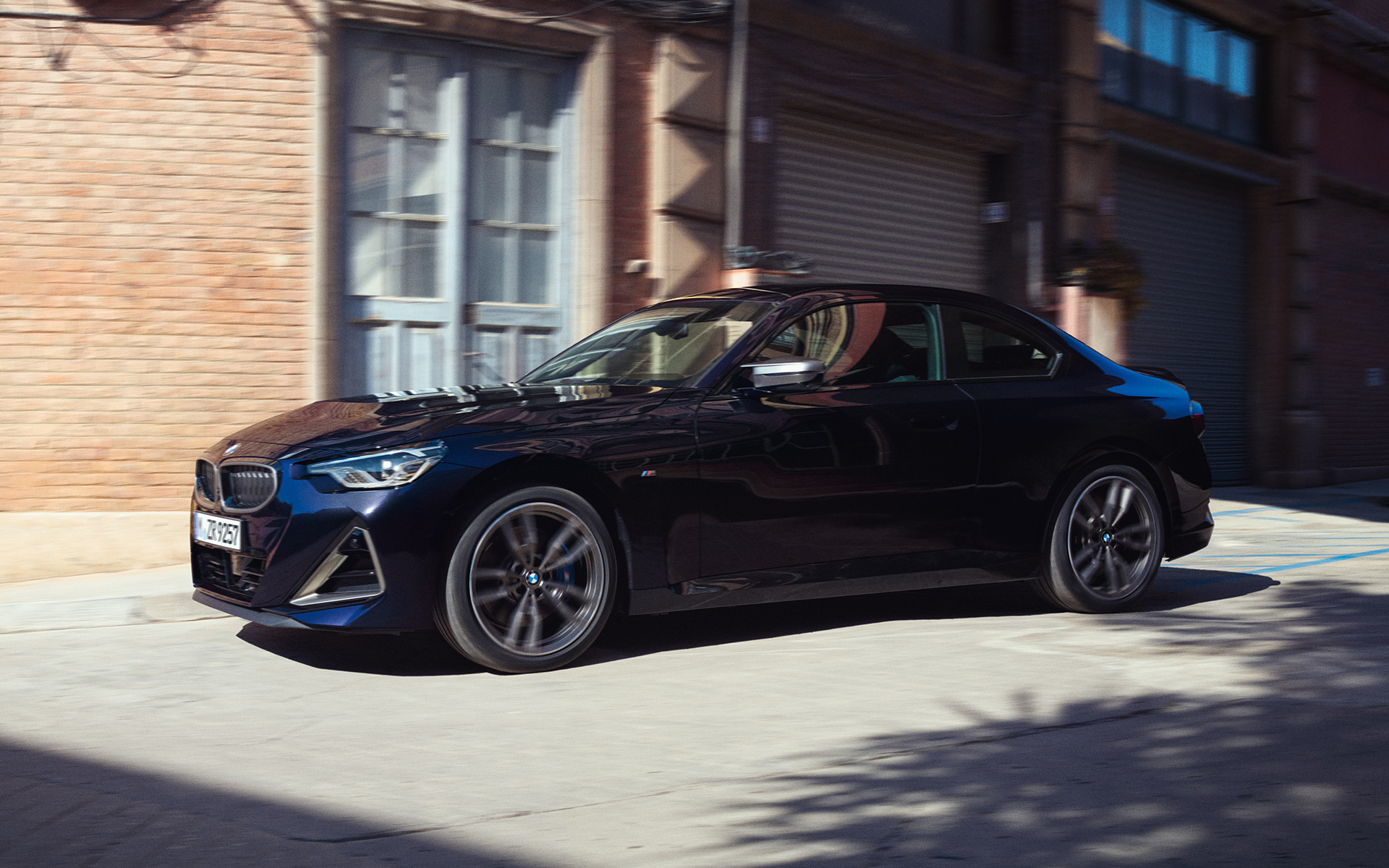 G42 BMW M240i xDrive雙門跑車Black Sapphire銀粉漆，停放於倉庫前，四分之三車側視角