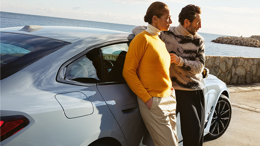 BMW Service Inclusive保養套裝，男人與女人倚靠在海堤邊的BMW i4旁