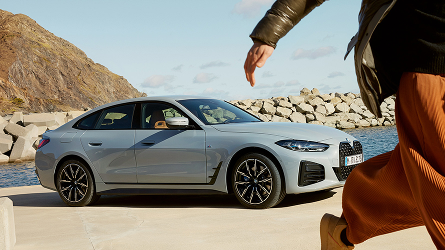 BMW Service Inclusive保養套裝，女人在海邊的BMW i4前走動